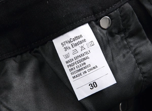 Detail of care label on black jeans showing 97% cotton material and size 30 information