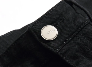 Vue détaillée du bouton en métal argenté et de la texture du tissu denim noir épais