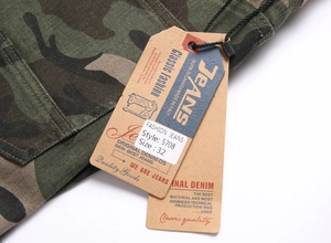 Detail of cotton camouflage cargo pants showing twill fabric texture and paper tags