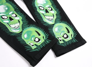Détail des imprimés crânes verts sur la jambe du pantalon en denim gothique noir