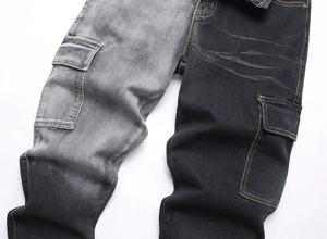 Detailed view of black and grey patchwork jeans with yellow contrast stitching and pockets