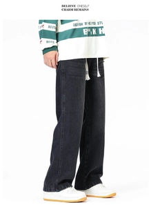 Détail d'un jean noir large avec délavage vintage et cordon de serrage blanc à la taille
