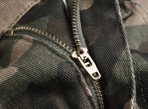 Macro detail of high-quality bronze zipper on camouflage cotton cargo pants