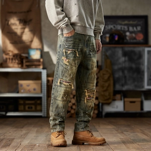 Vintage loose-fit distressed men's jeans with American flag patches and yellow mud wash finish