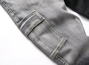 Detail of grey washed denim cargo pocket with contrasting orange stitching and rugged texture