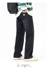 Détail d'un jean baggy noir délavé avec un écusson carré orange sur la poche arrière