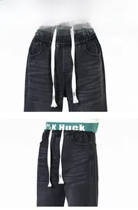 Détail du jean délavé avec taille élastique et impression de lettres vertes