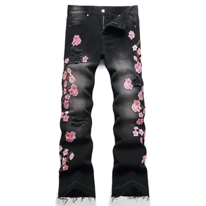 Men's flared black jeans featuring heavy cherry blossom embroidery and distressed details