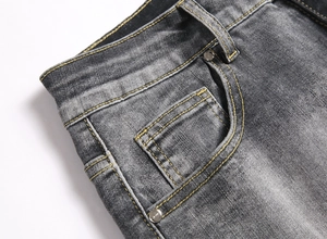 Detail of yellow double stitching and rivet on grey washed denim jeans fabric