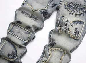 Vue détaillée d'un jean évasé bleu clair avec délavage prononcé et broderies noires