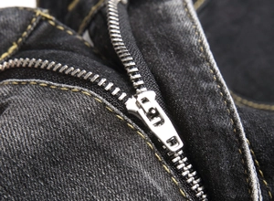 Macro shot of metal zipper with yellow contrast stitching on dark denim cargo pants