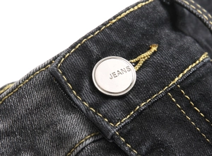 Macro shot of silver metal jeans button and contrast stitching on black-grey denim fabric