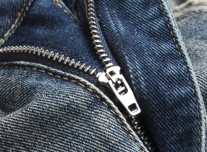 Gros plan détaillé sur la fermeture éclair en métal et la texture denim du jean bleu