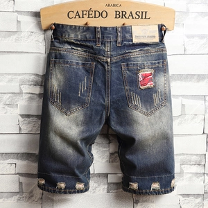 Men's loose distressed denim shorts with ripped details and red camo patch design