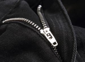Detailed macro view of the silver metal zipper on black heavy-embroidery denim jeans