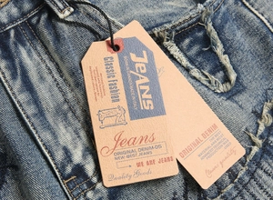 Détail du tissu denim bleu délavé avec effet stone wash et étiquettes de marque en papier