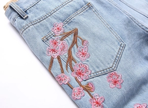 Gros plan de la broderie de fleurs roses et de la texture denim sur la poche arrière du jean