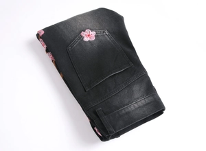 Detailed pink cherry blossom embroidery on the back pocket of black flare denim jeans