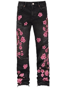 Detail of pink cherry blossom embroidery and distressed rips on black flared jeans