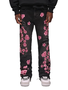 Detail of pink cherry blossom embroidery and distressed denim on men's black flared jeans