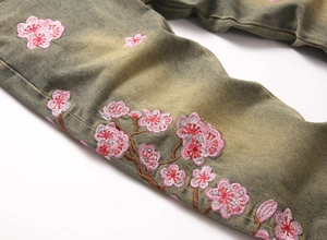 Macro detail of pink sakura embroidery and dirty wash vintage texture on denim jeans