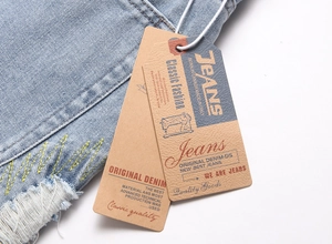 Detail of light blue denim fabric featuring yellow stitching and a paper hangtag