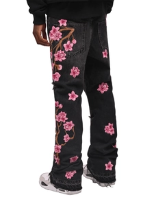 Macro detail of high-quality pink cherry blossom embroidery on washed black denim jeans