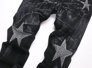 Detail of star-shaped patch with black rhinestones on washed black flare jeans
