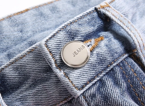 Detailed macro view of the silver metal button with JEANS engraving on blue denim pants