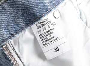 Detail of blue denim jeans wash tag showing 97% cotton material and size 30 label