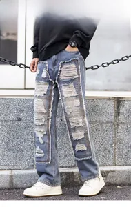 Detail of men's distressed denim jeans with heavy patchwork and frayed edge accents