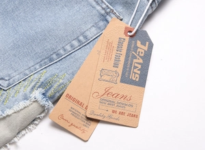 Detail of light blue denim hem with distressed fringe and vintage textured hangtags