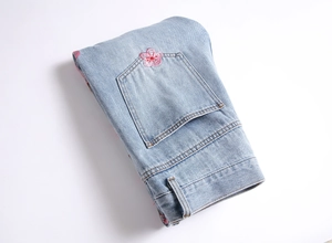 Détail du jean bleu clair avec broderie de fleurs de cerisier roses sur la poche