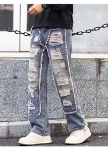 Detailed view of heavy distressed rips and whiskers on men's streetwear denim jeans