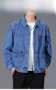 Detail of heavy denim jacket in dark blue with orange embroidery and metal buttons
