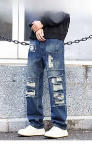 Detail showing heavy distressed rip design and frayed edges on men's vintage blue jeans