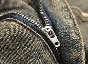 Detailed macro view of high-quality silver metal zipper on vintage washed blue denim pants