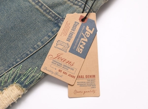 Detailed close-up of distressed denim jeans featuring waist stitching and vintage ripped hems
