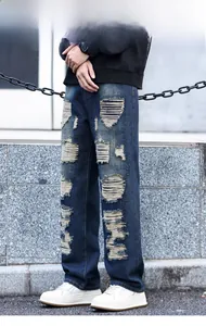 Gros plan sur les détails usés, le tissu denim épais et le genou déchiré du jean homme