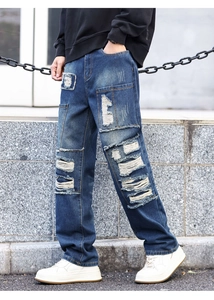 Detail view of retro blue distressed denim jeans with heavy ripped patches and frayed edges