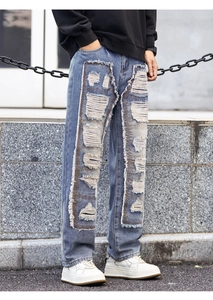 Detail of ripped distressed blue jeans with heavy patchwork and frayed edges