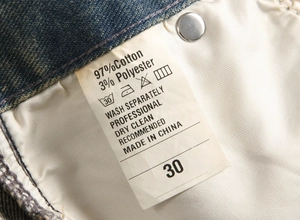 Close-up of denim jeans care label showing material composition and washing instructions