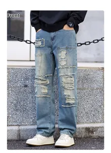 Close-up of distressed light blue denim jeans with heavy ripped details and patches