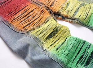 Close-up of rainbow gradient fringe and heavy-duty distressed denim fabric details