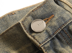Close-up of vintage slim fit jeans with silver button detail and yellow stitching