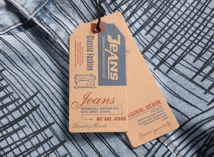 Close-up of khaki cardstock tags on slim flare jeans with black line print details
