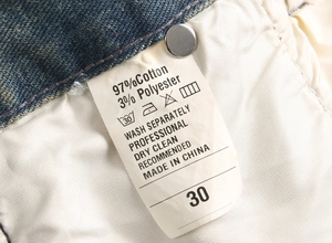 Detailed macro view of denim jeans care label showing 97% cotton fabric composition