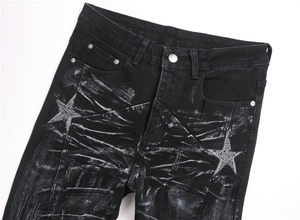 Detail of black flared jeans with white spray effect and rhinestone star patches