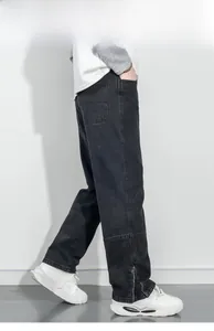 Détail du pantalon en jean noir avec ourlets zippés et coutures style cargo modernes