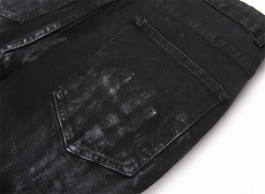 Detailed view of black marble wash denim fabric and stitched back pocket on flare jeans